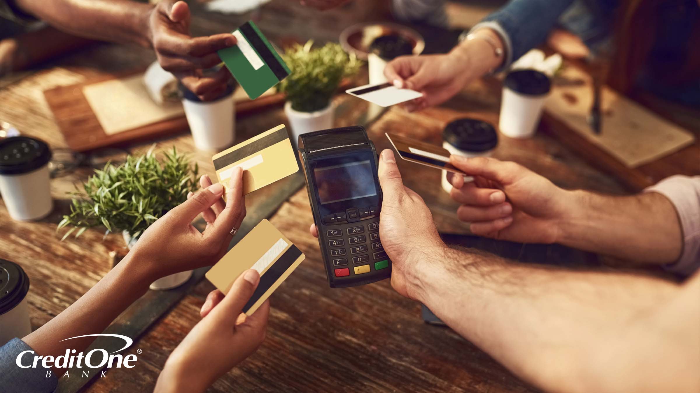 Six hands each hold a credit card toward a restaurant server’s handheld point-of-sale system. If each person has a card that rewards dining out, they may be trying to maximize that benefit.