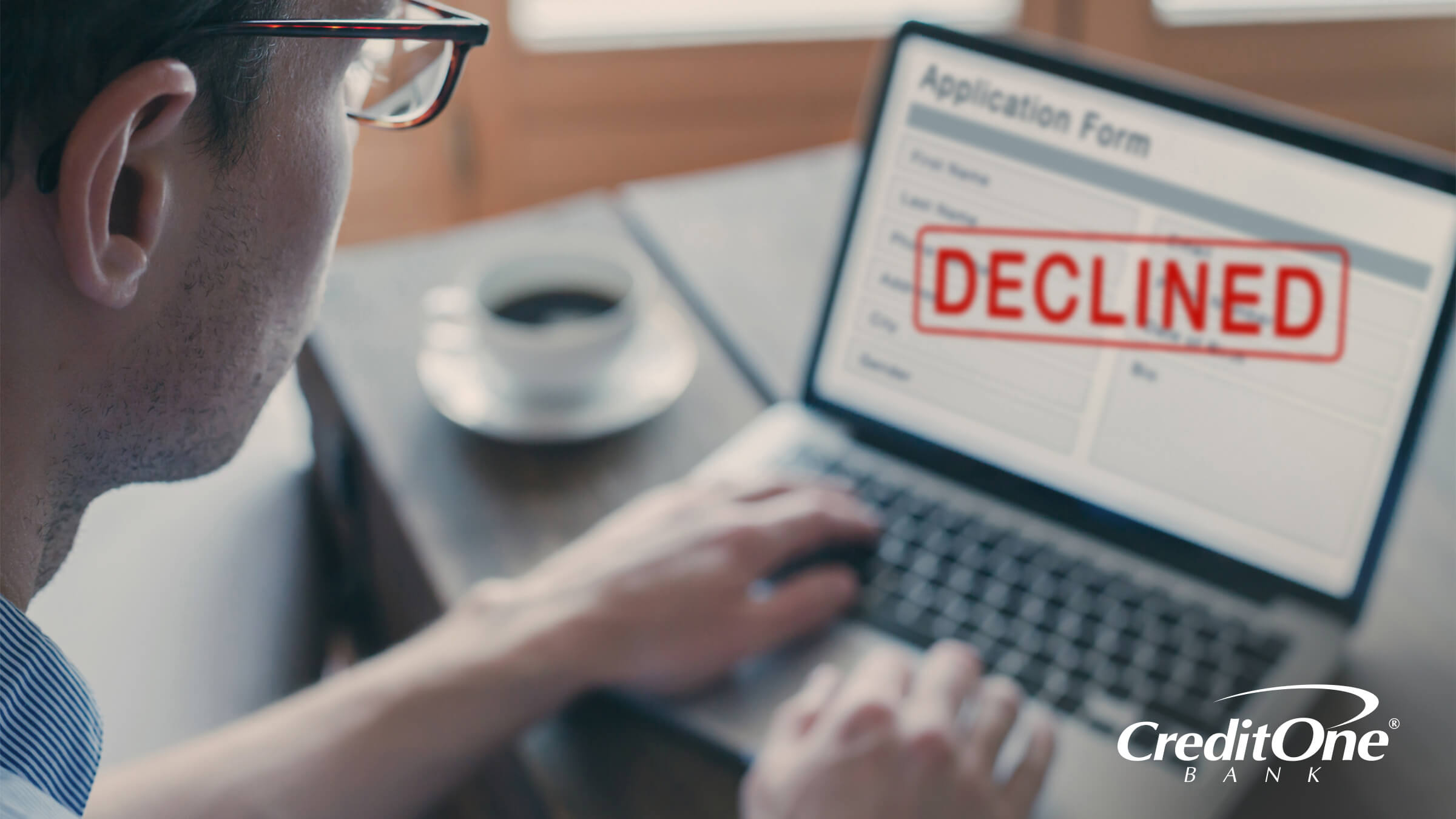 A man’s laptop screen shows an application form that has been declined, which may be due to having poor credit and could come with hidden costs.