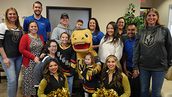 Credit One Bank employees pose for a photo with local family at Candlelighters headquarters