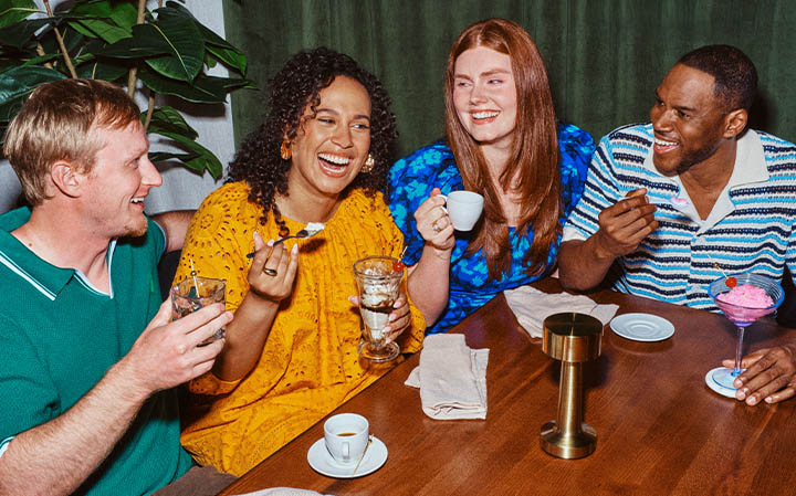 A group of four friends dining and laughing around a table