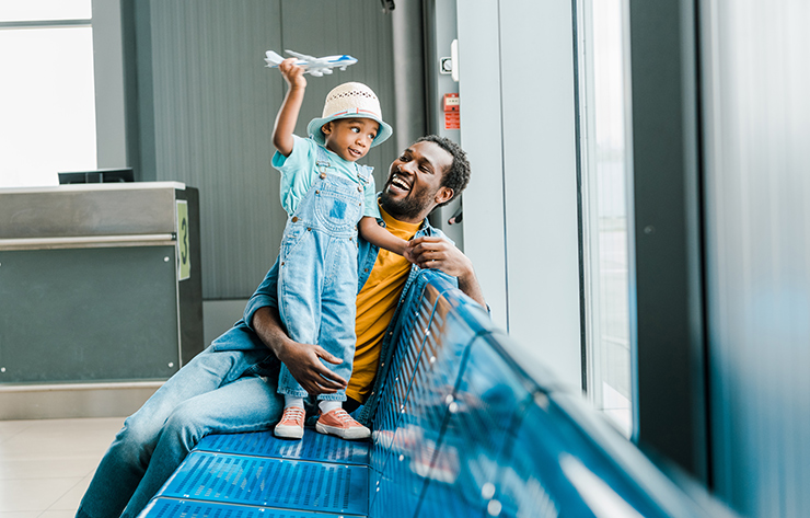 A happy father and young child at the airport playing with a toy plane